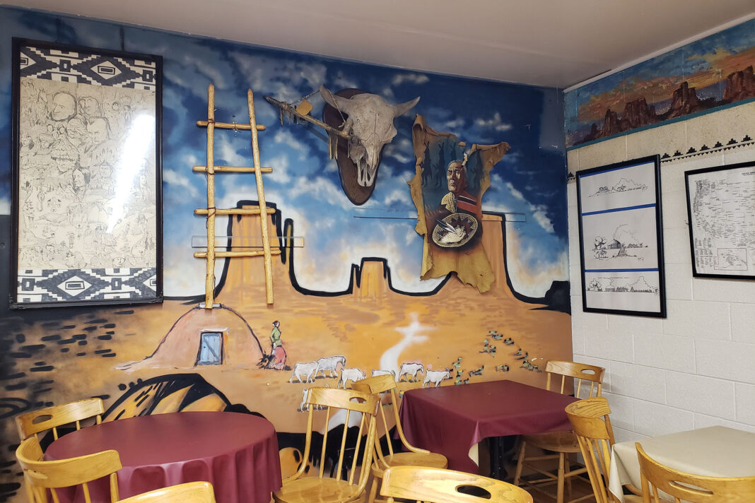 Native American regalia hanging on a wall painted with a desert landscape
