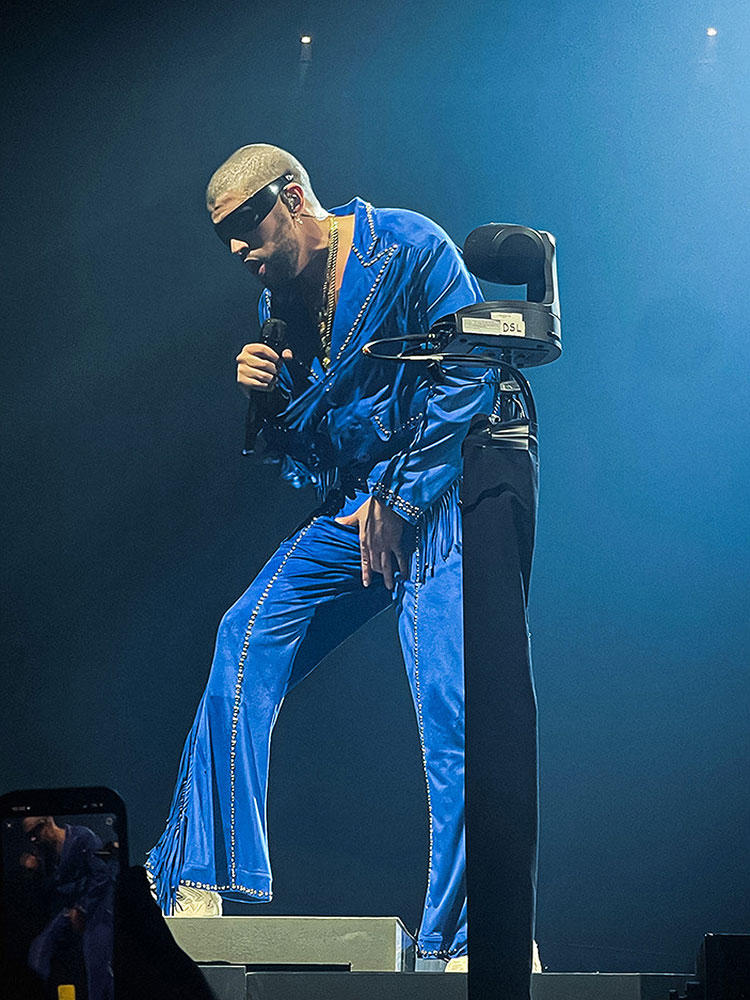 Bad Bunny performing on stage while wearing a blue suit