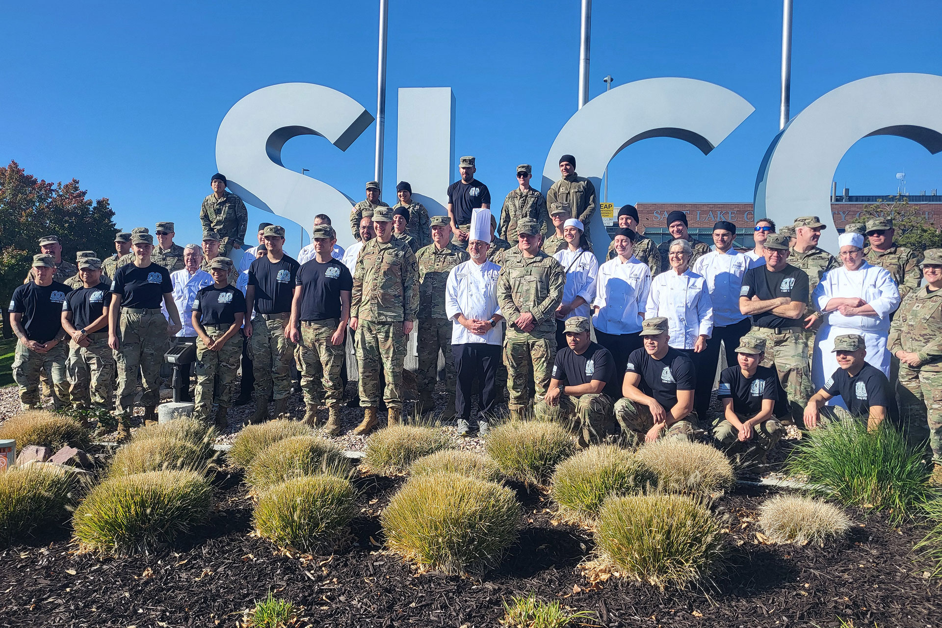 A group photo of student chefs, faculty and military personnel