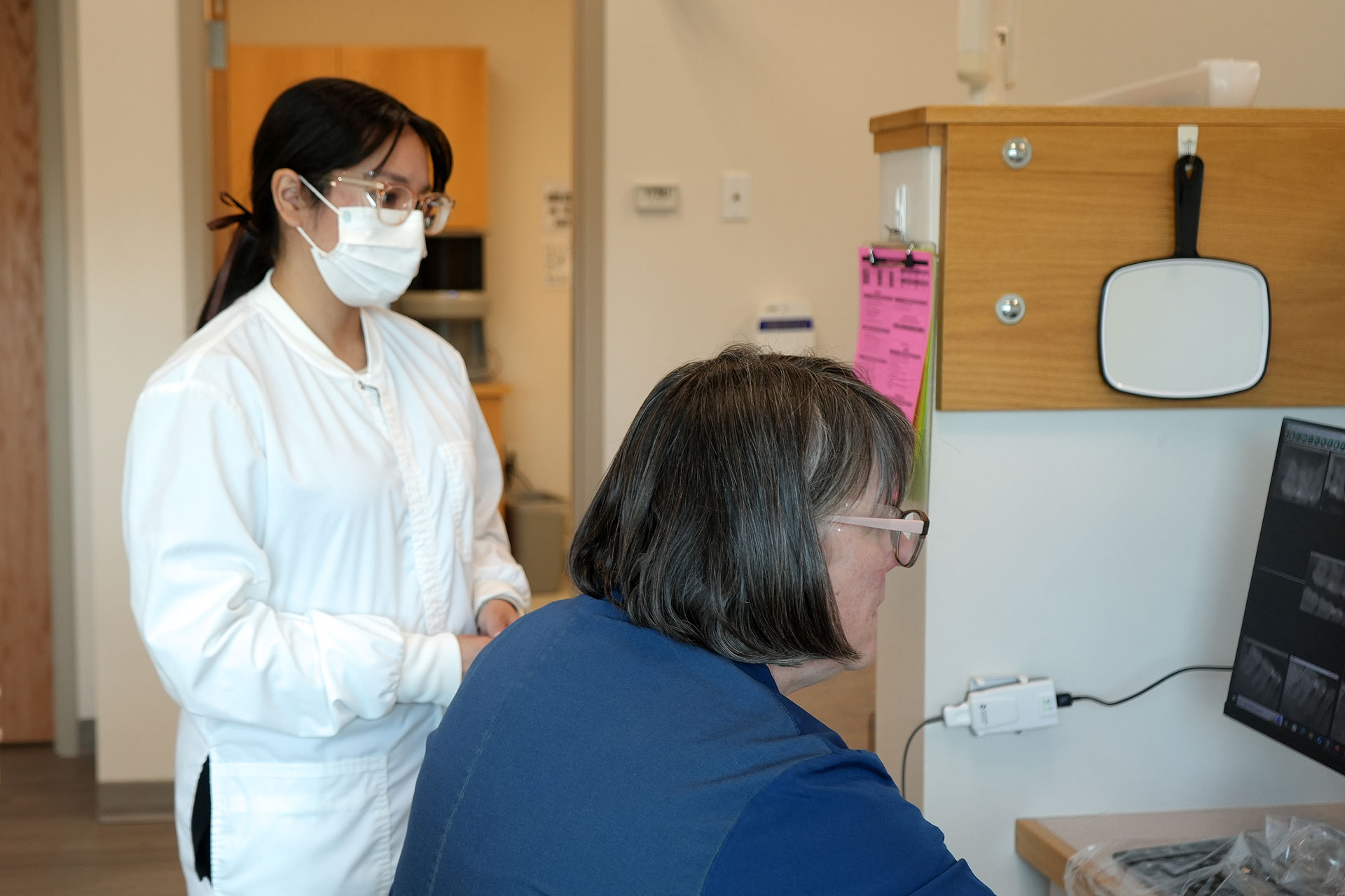 Dental hygiene student and instructor review x-rays on a computer screen