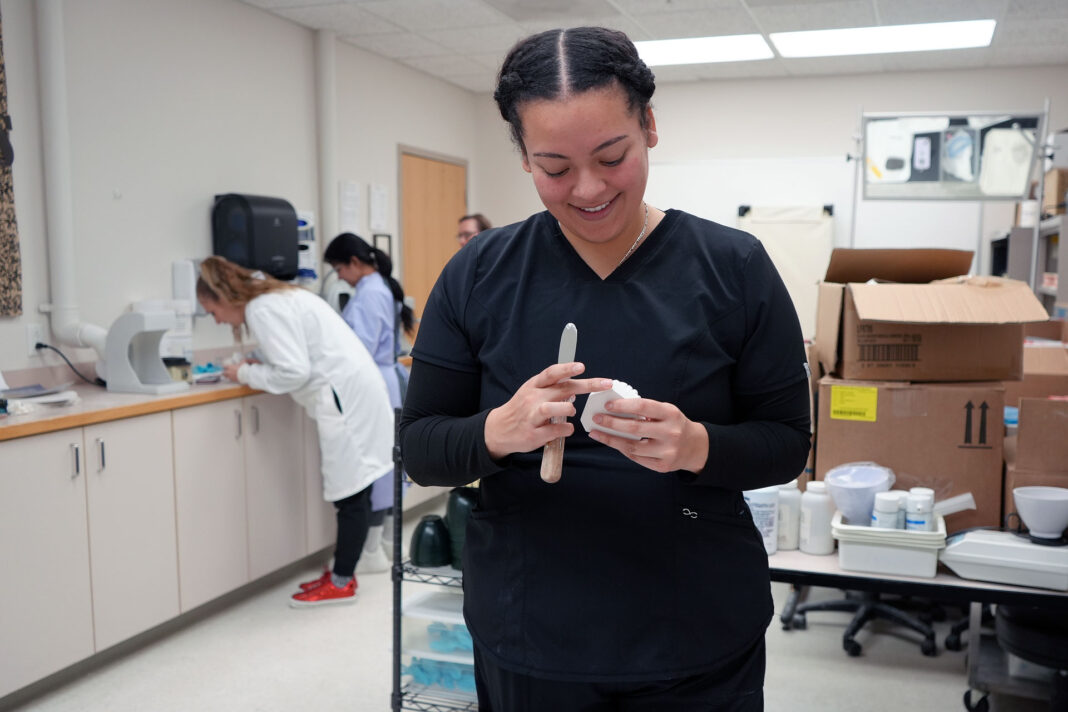 Dental hygiene student wearing black scrubs and learning about dental materials