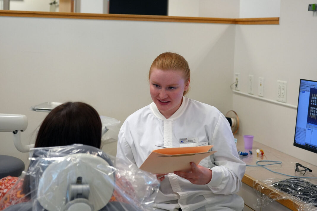 Dental Hygiene student holding records and talking with a patient