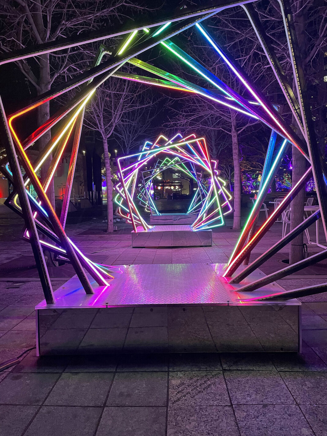 Illuminated square rods artistically displayed in rotation on multiple bases to create a portal effect