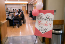 Students come together to support local artisans at Valentine’s-themed market Poster reads "Valentine Vendor Day" next to open doorway where vendors sell items