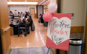 Students come together to support local artisans at Valentine’s-themed market Poster reads "Valentine Vendor Day" next to open doorway where vendors sell items