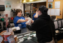 Warm up with the What’s Bruin coffee kiosk Cori giving food to a customer