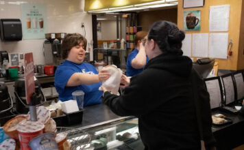 Warm up with the What’s Bruin coffee kiosk Cori giving food to a customer