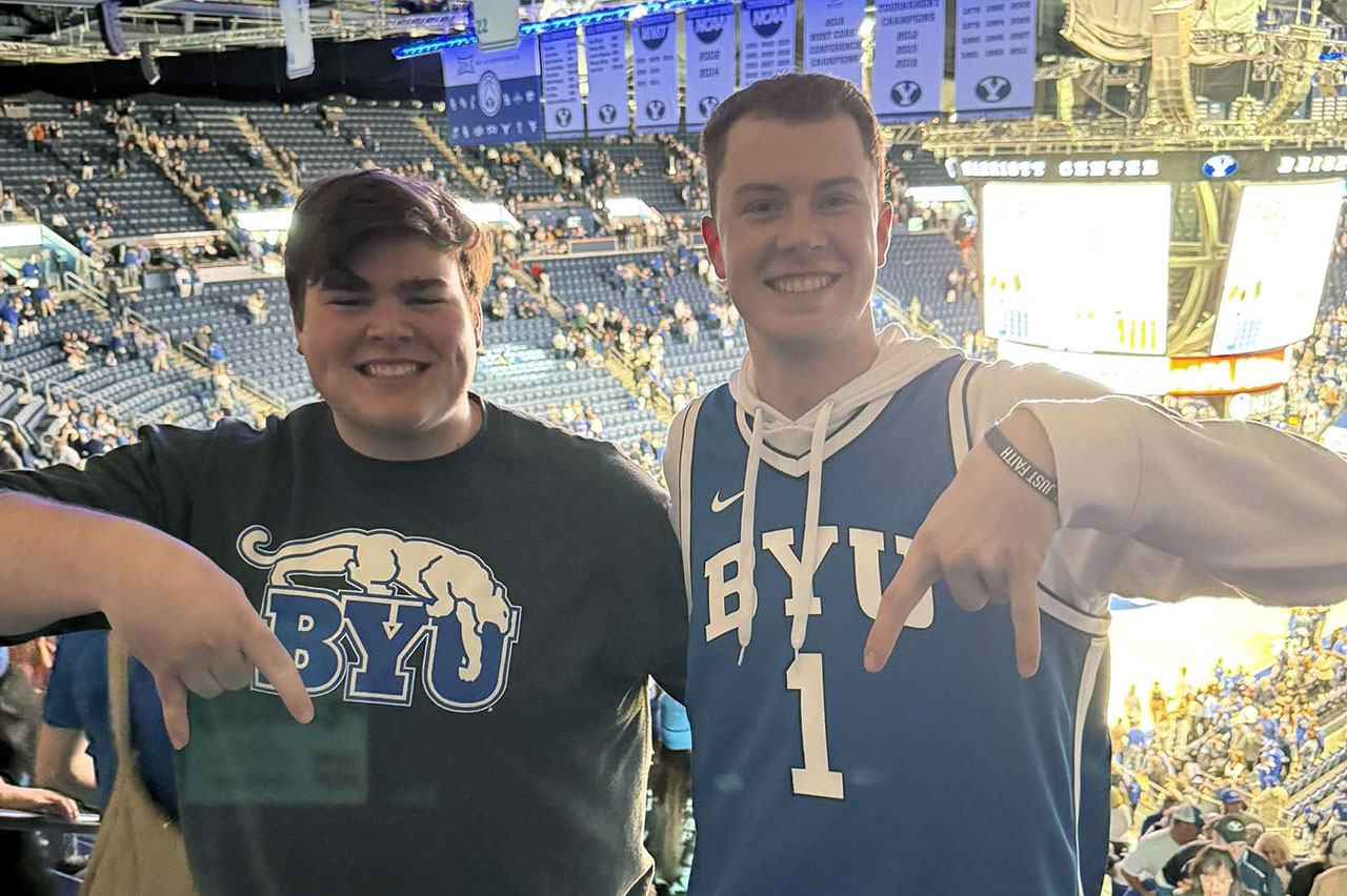 Two fans giving the "Hook'em Horns" sign upside down