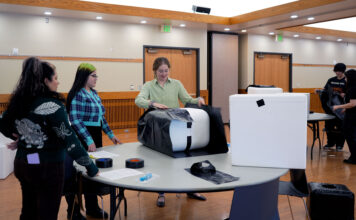 SLCC community builds winter shelters for outdoor cats Lead volunteer assembling a cat shelter as others watch