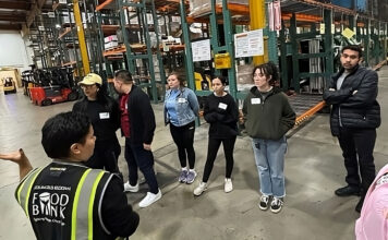 Spring break alternative provides a meaningful experience Food bank employee wearing a fluorescent vest speaking to volunteers