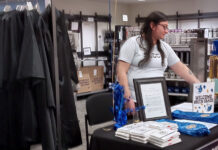 Cuenta regresiva para la inauguración de SLCC: Celebrando un nuevo capítulo Avelina working at a table surrounded by graduation items for sale