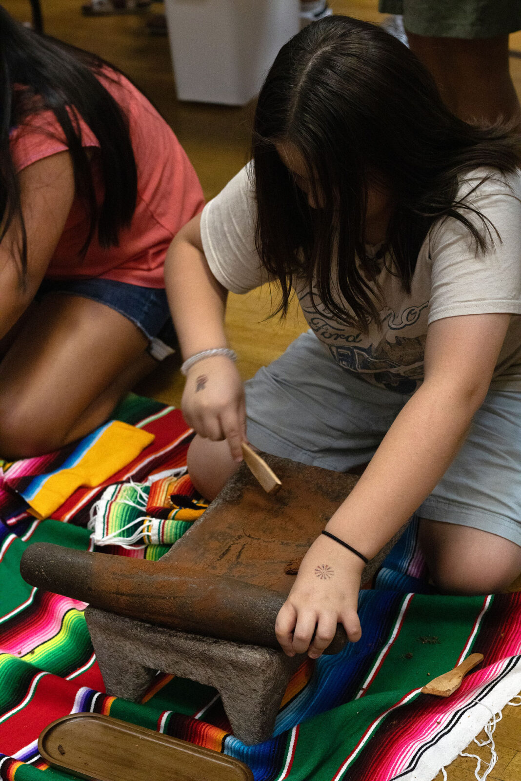 Young woman using a metate for cocoa beans