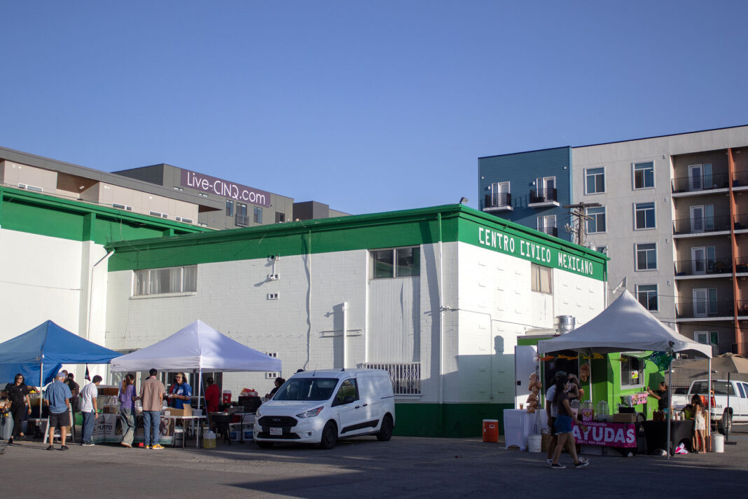 People gathering in front of a white building with green trim