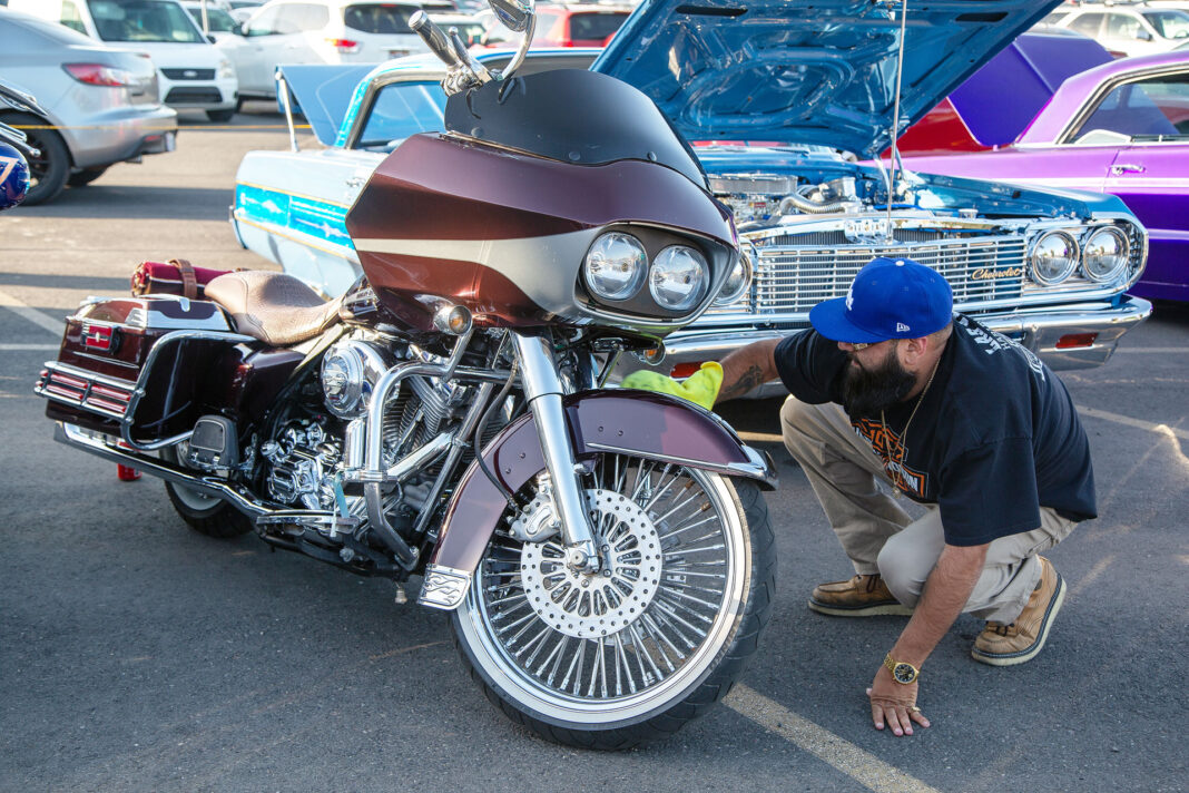 Man wearing blue ball cap polishing his motorcycle