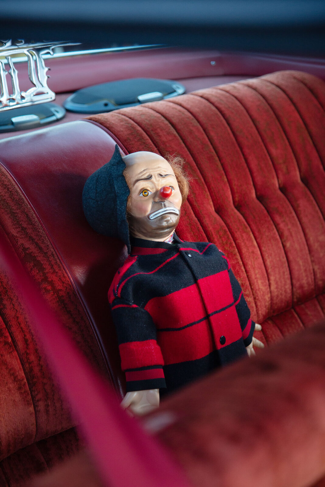 Chicano doll in the back seat of a lowrider