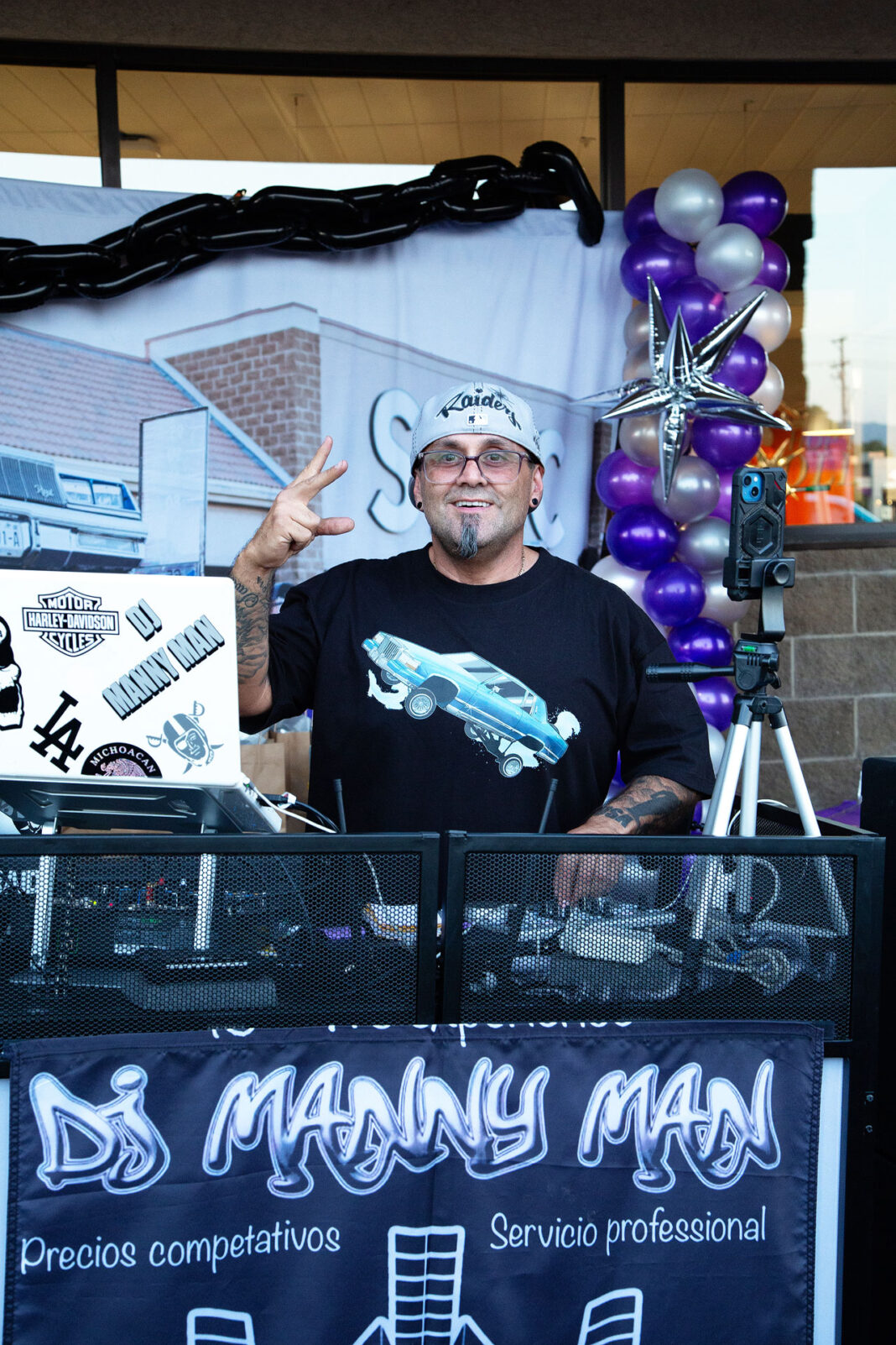 DJ smiling and posing for a photo behind his setup