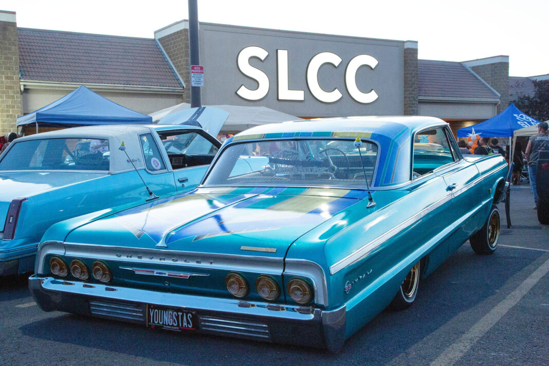 Lowriders parked in front of campus building lit up by large SLCC letter sign