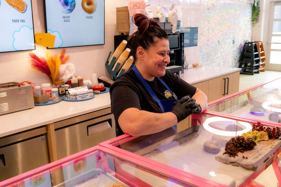 Donut shop worker Charene smiling behind the counter