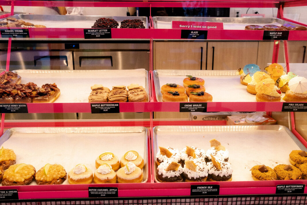 Three rows of donuts on display inside a glass case