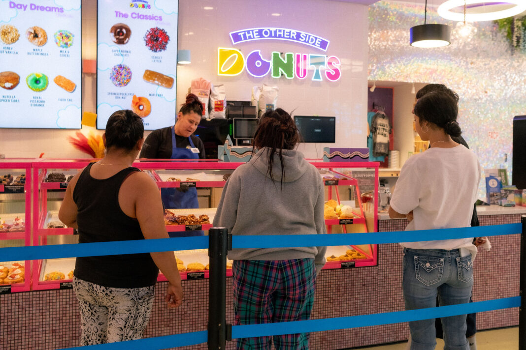 Multiple customers standing in a donut shop while Charlene works