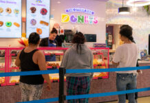The Other Side’s donut shop tells community, ‘Donut give up on your dreams’ Multiple customers standing in a donut shop while Charlene works