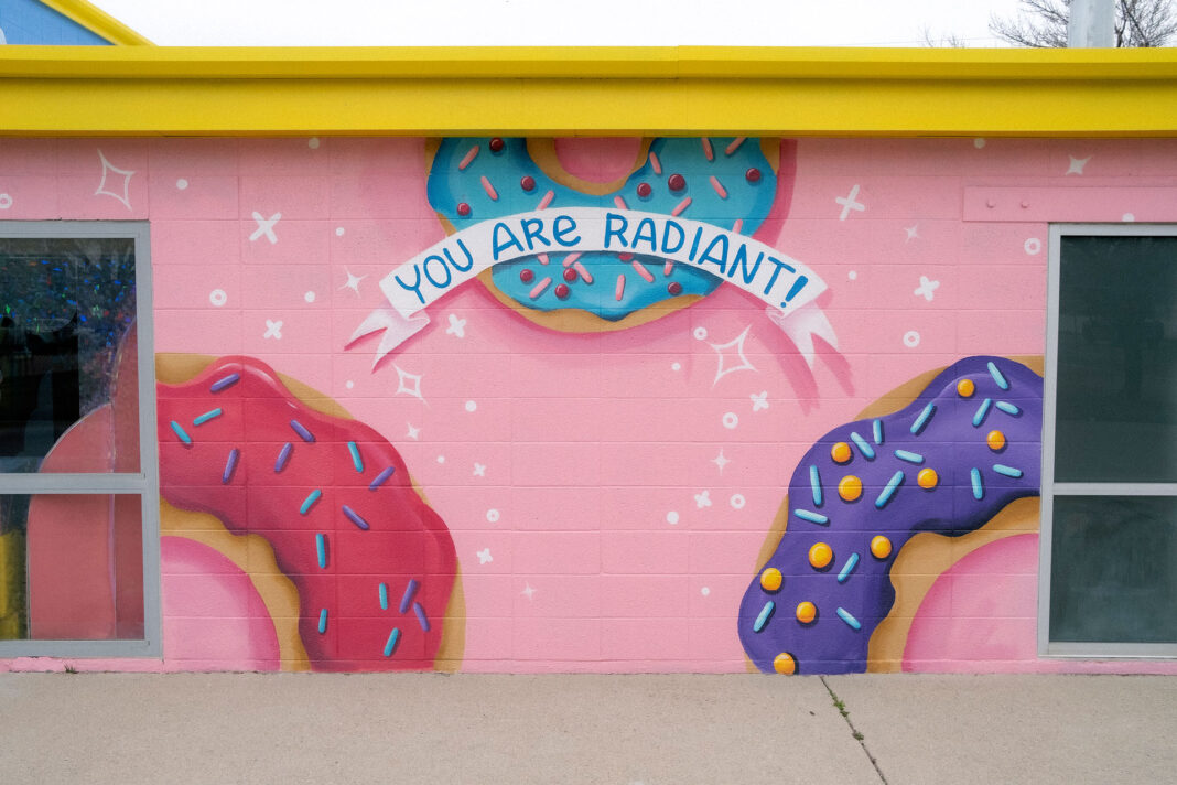 Wall painted in pink with frosted donuts and the words "You are radiant!"