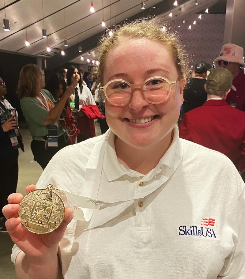 Bess Hayes smiling while holding her gold medal