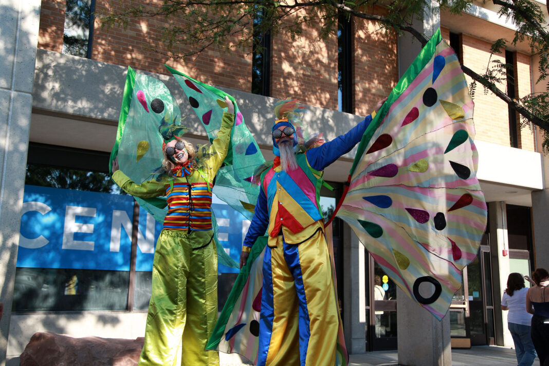 Two stilt walkers spreading their costume butterfly wings