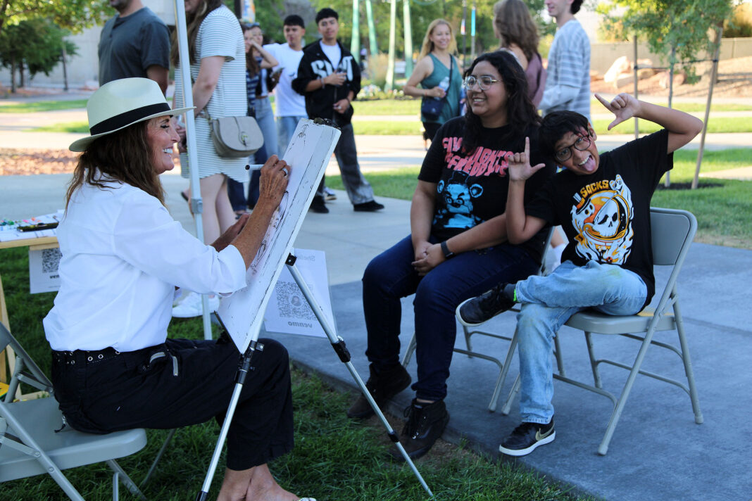 Two people laughing and smiling while getting their picture drawn