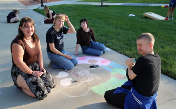 Back to school, with a bash! Four people contributing to a chalk art drawing