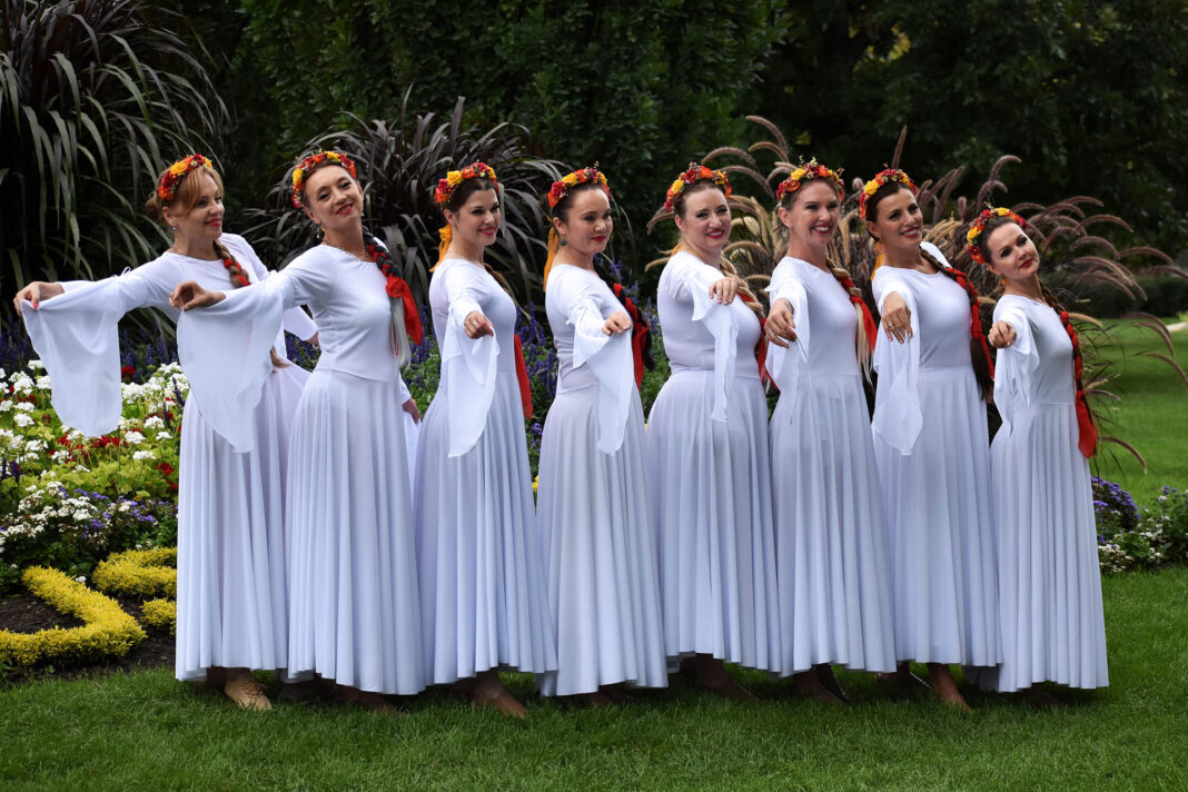 Dancers wearing white dresses and red floral headbands