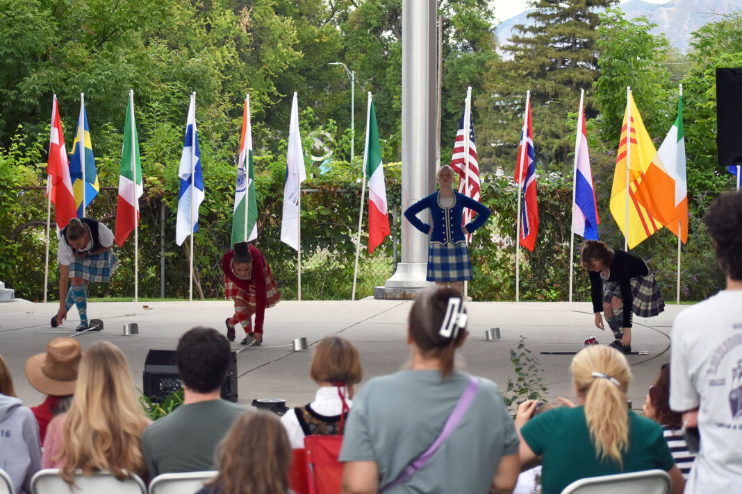Four dancers performing under a gazebo as spectators observe