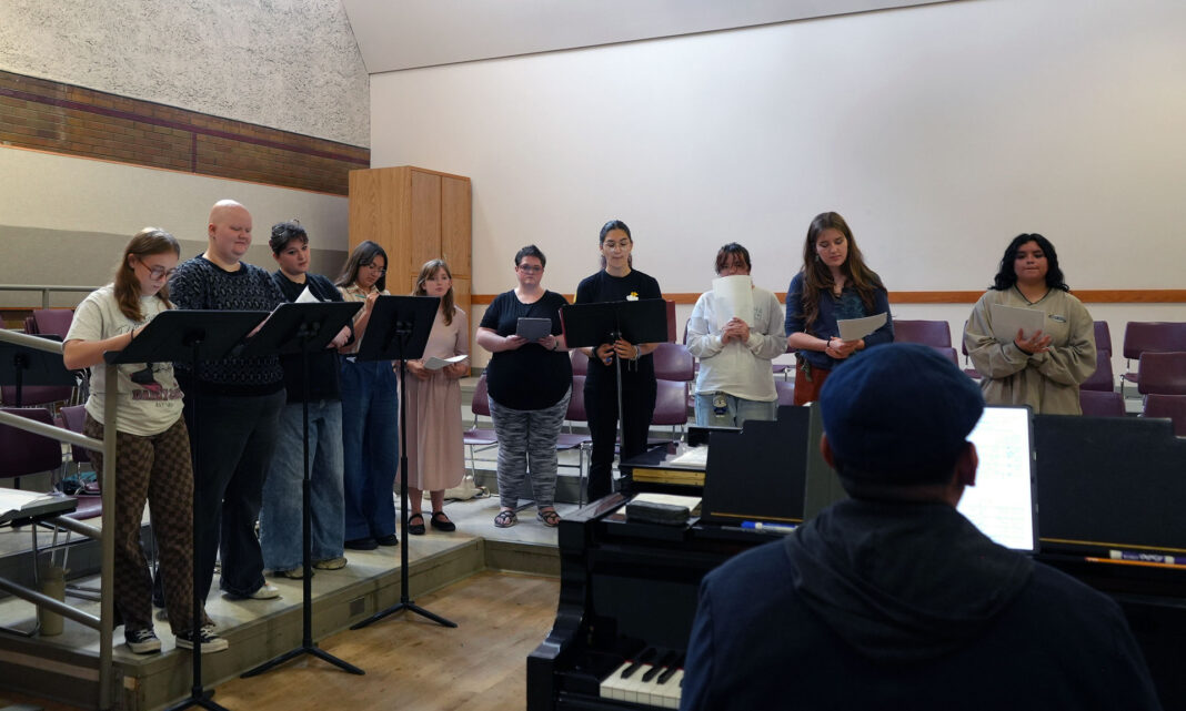 Juan playing piano as choir students sing a song