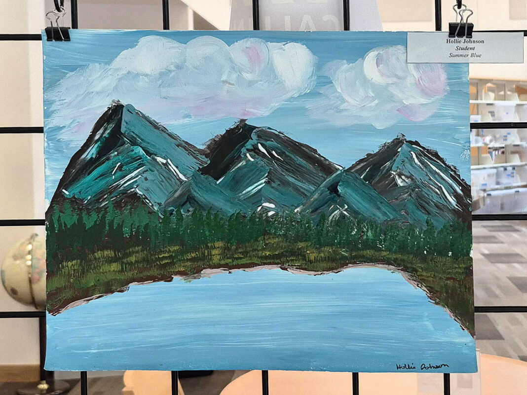 Painting of mountains and a lake being displayed in a library