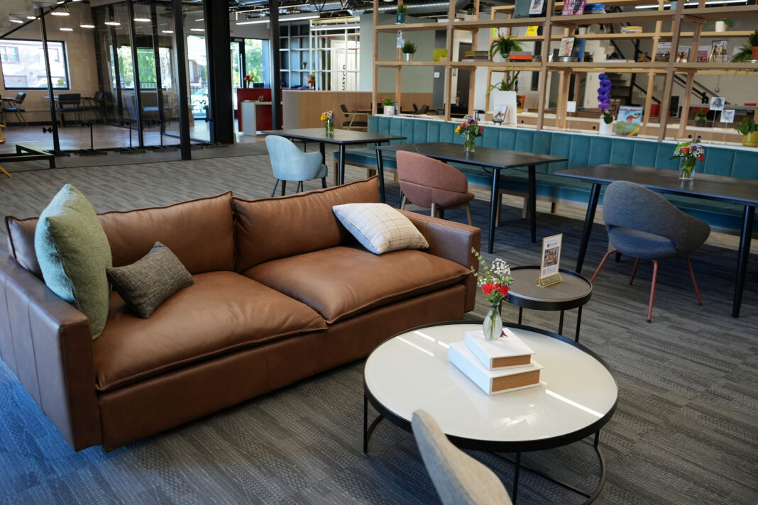 A lounge area including a brown couch, pillows, coffee tables, and tables and chairs
