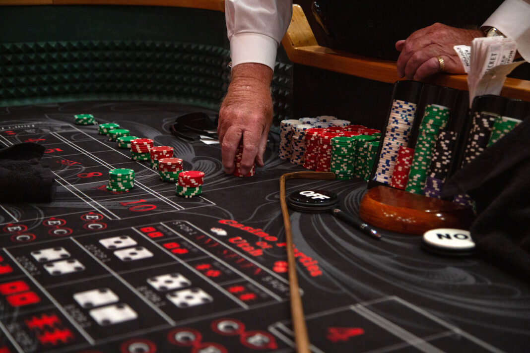 Craps dealer's hand holding a stack of red casino chips on a craps table