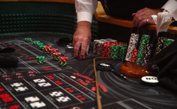 Photos: Casino Night energizes Redwood campus Craps dealer's hand holding a stack of red casino chips on a craps table