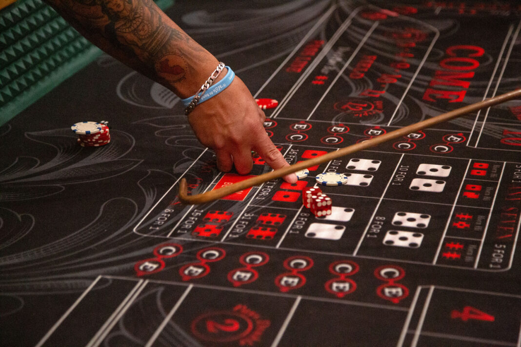 Craps dealer pointing to a betting option on a craps table