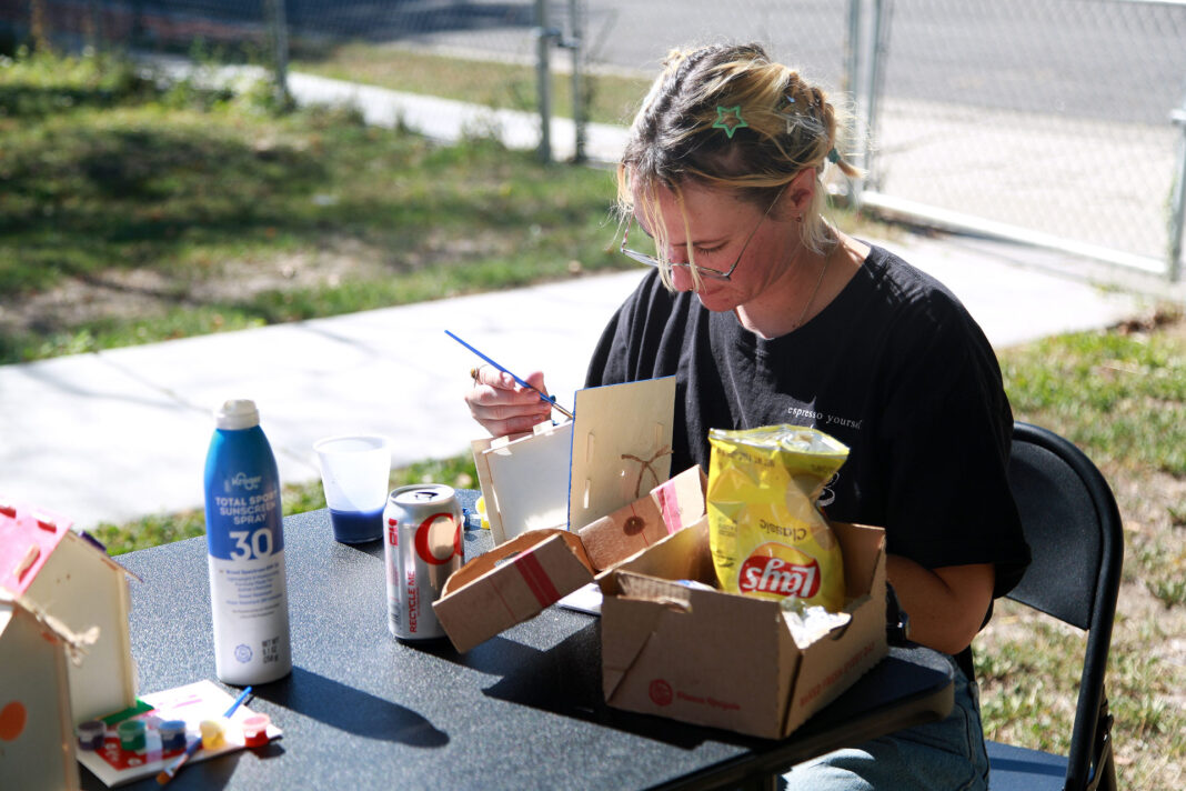 Young person painting a birdhouse