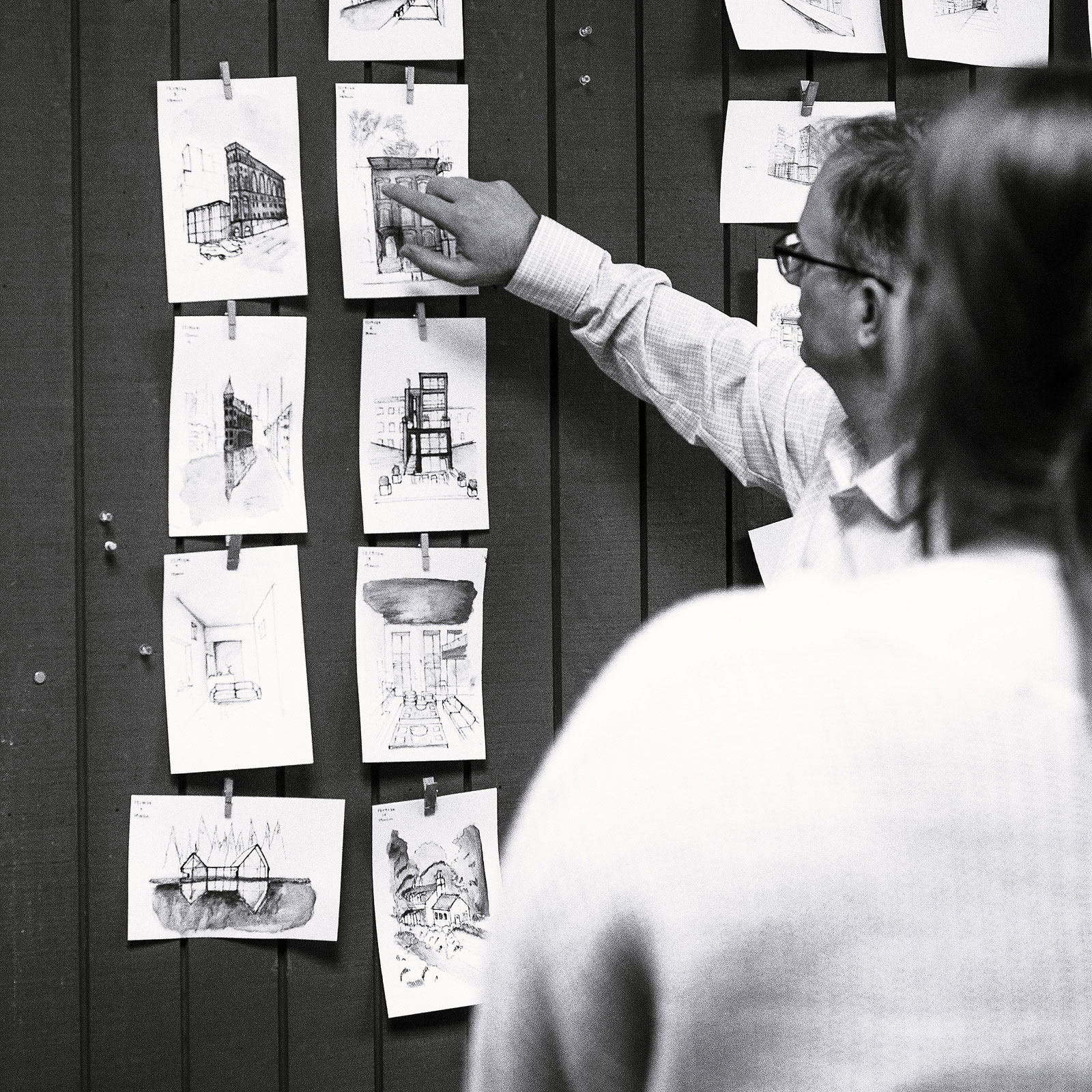 Black-and-white photo of an instructor discussing sketches with a student