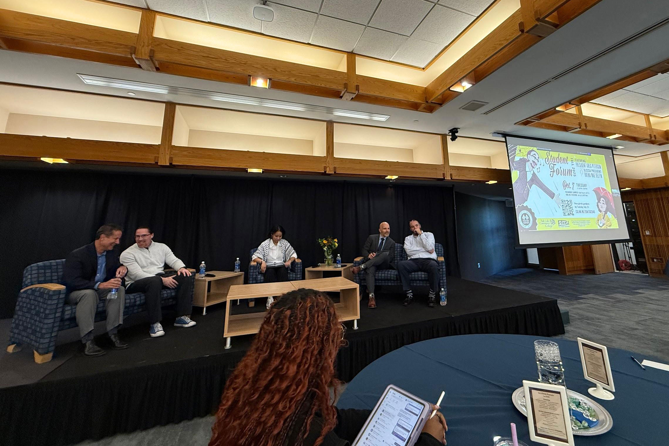Panelists sitting in chairs on a riser