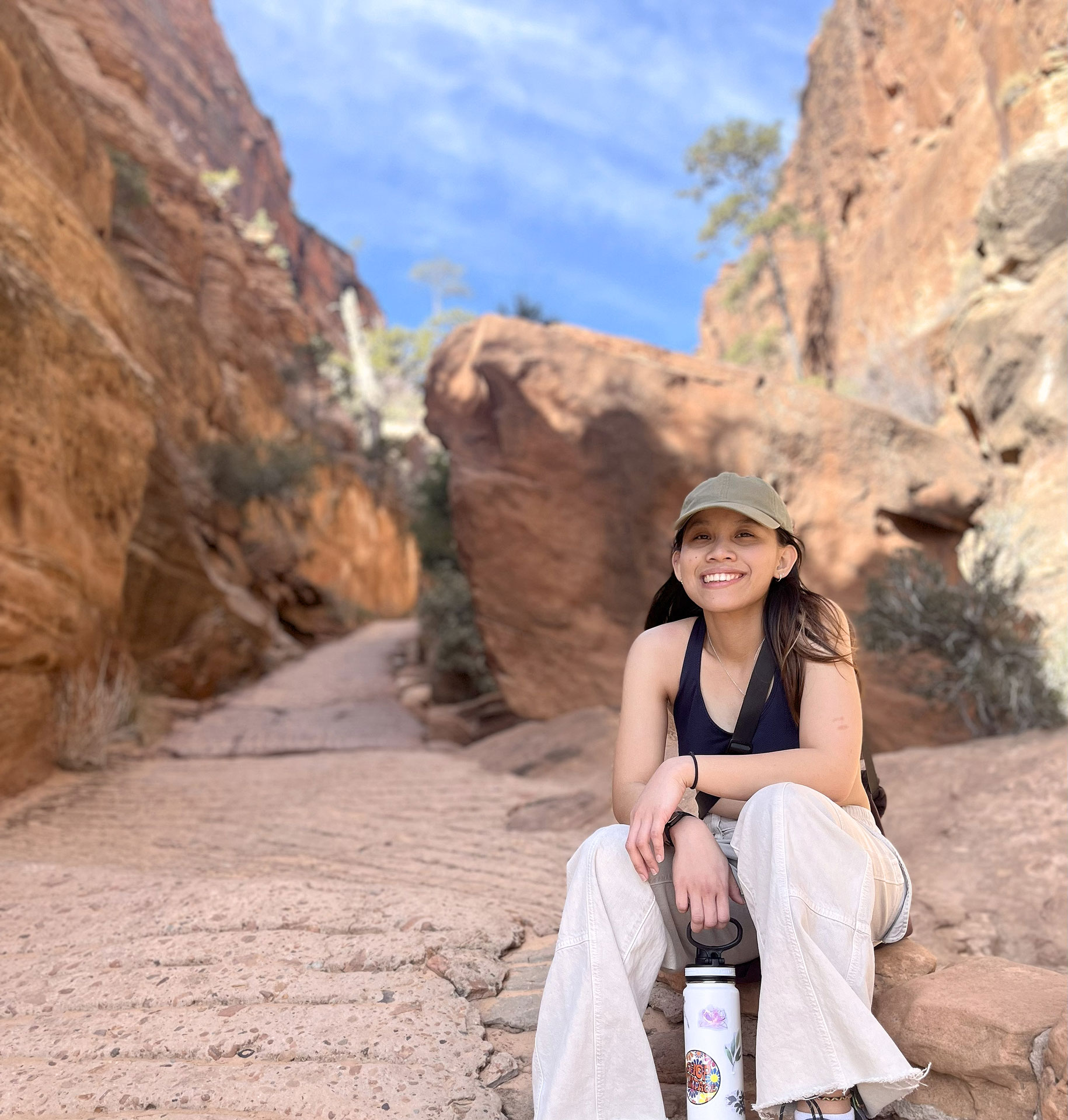 Roena sitting down surrounded by red desert rocks