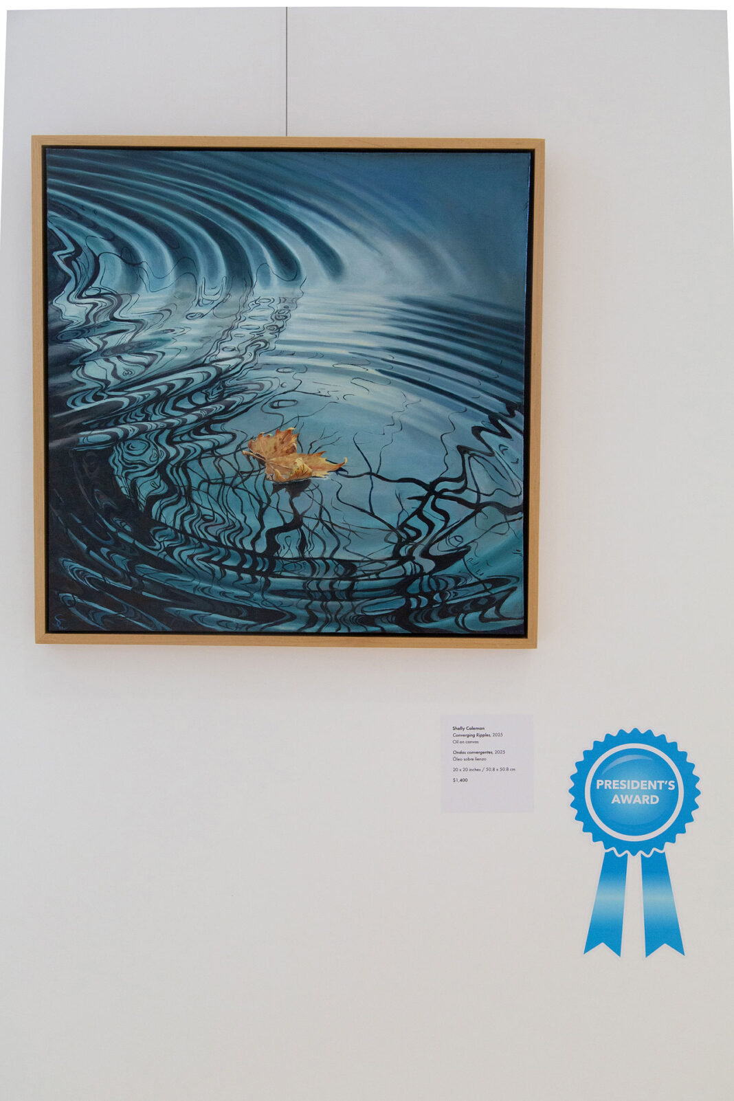 Painting hanging on a wall with a light blue colored ribbon signifying the president's award winner