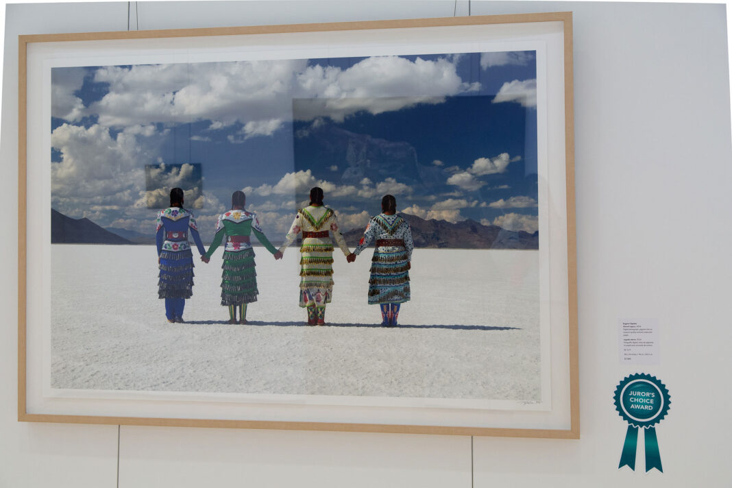 Framed photograph hanging on a wall with a teal colored ribbon signifying the juror's choice winner