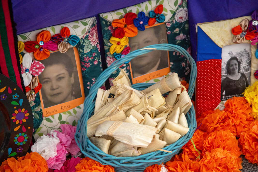 Tamales in a blue basket next to portraits and orange flowers