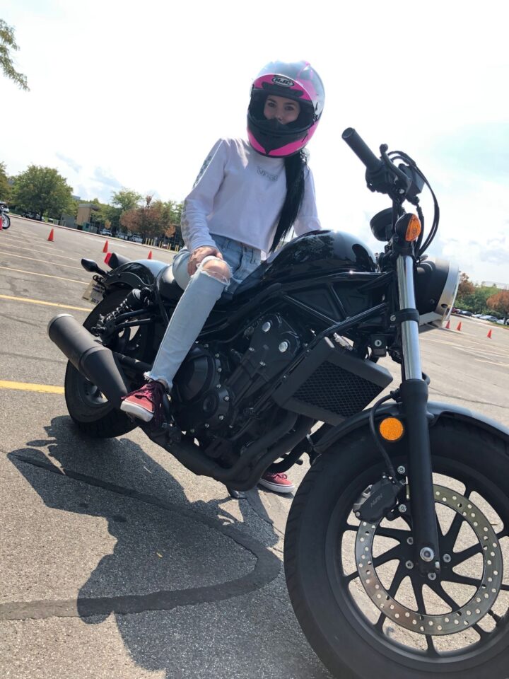 Katelyn wearing a helmet while seated on her motorcycle