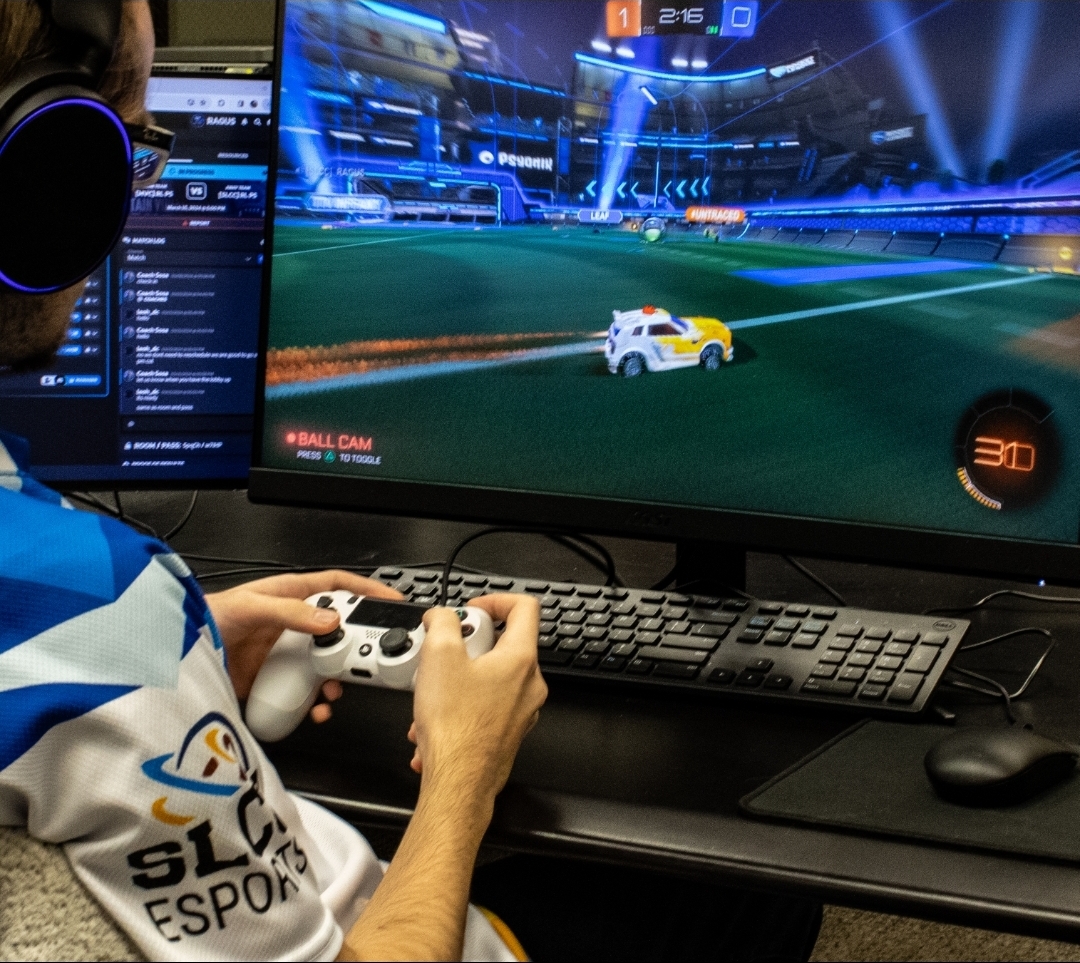 esports player using a controller in front of monitor displaying "Rocket League" gameplay