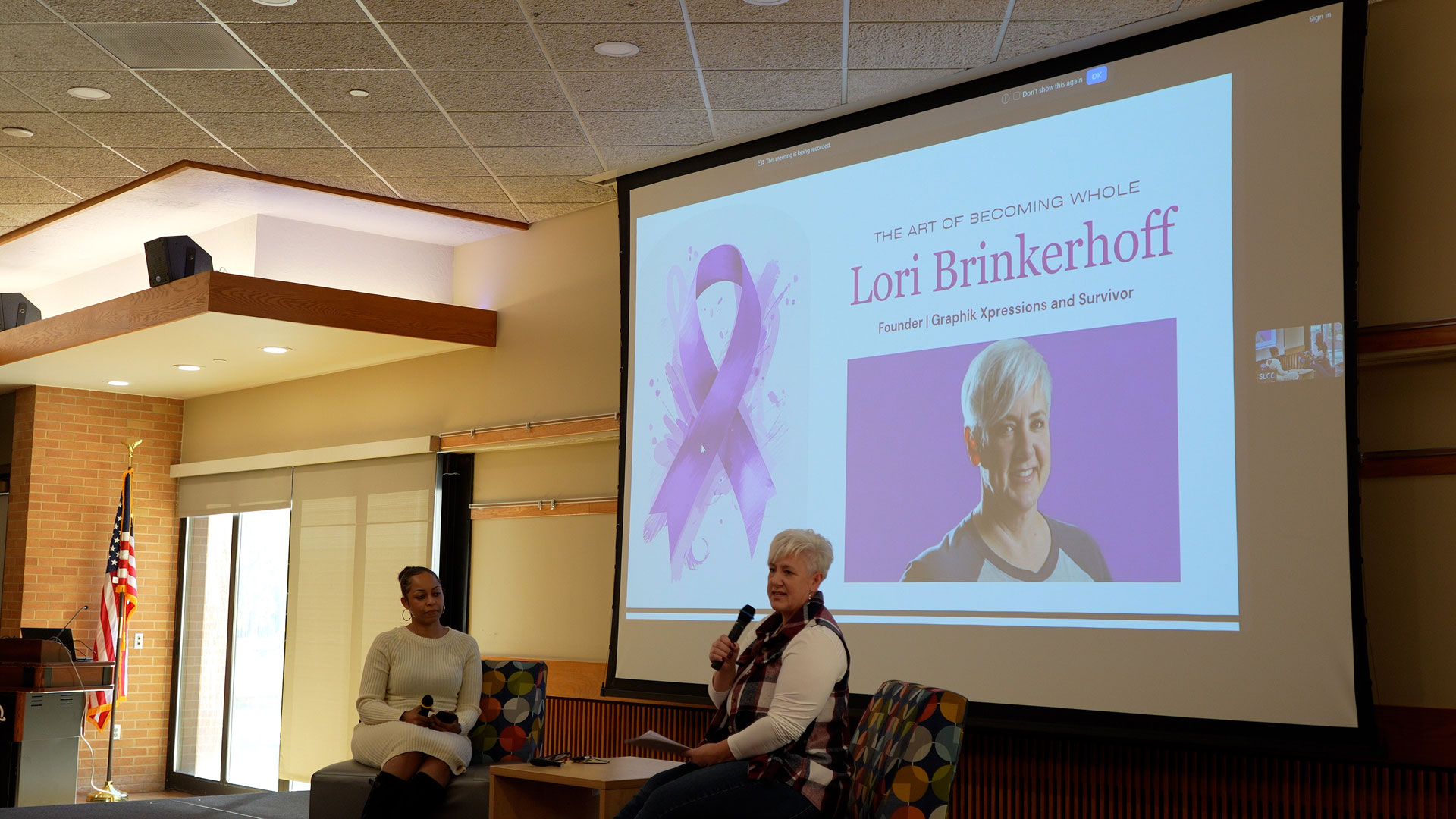 Lori talking to attendees from on stage as Chenoa listens