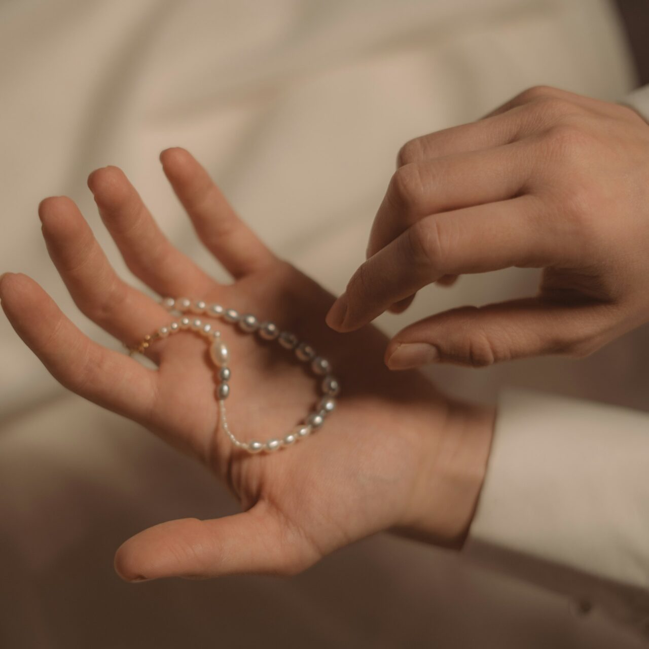 a person's hands holding a pearl bracelet