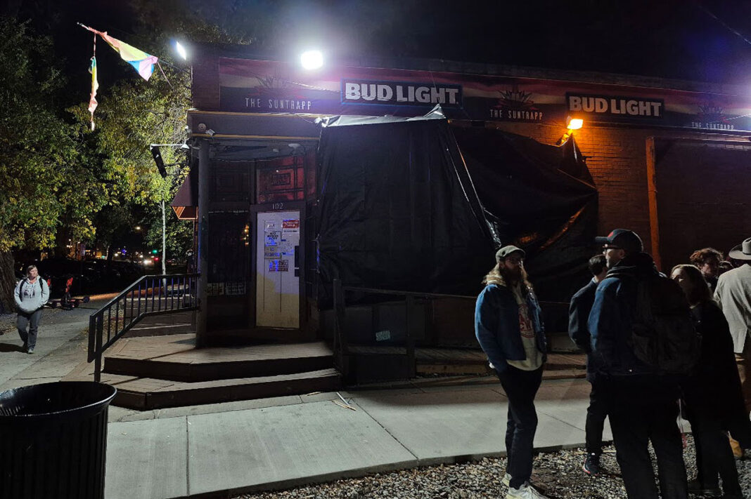 People standing outside The Suntrapp bar at night